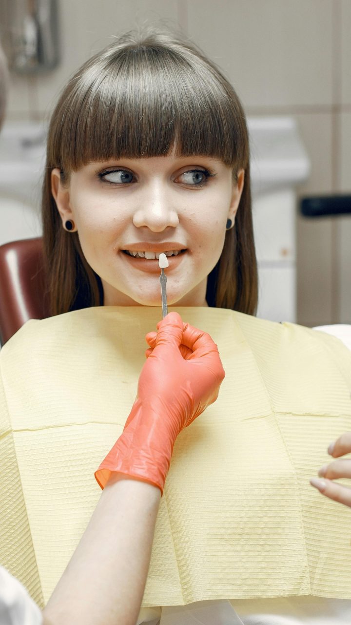 Patientien beim Zahnarzt bekommt Veneer vorgehalten und prüft die Optik